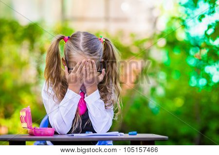 Adorable school girl at desk with notes and pencils outdoor. Back to school.