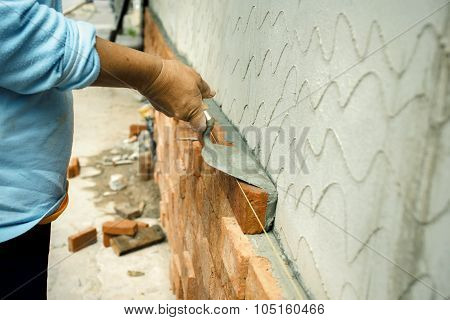 Applying construction trowel with brick wall