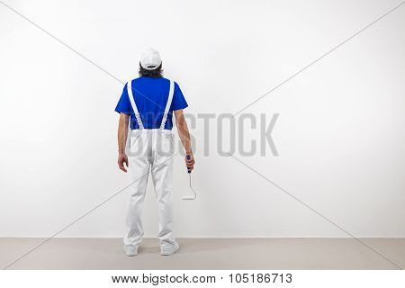 Painter With Paintroller Looks At White Wall