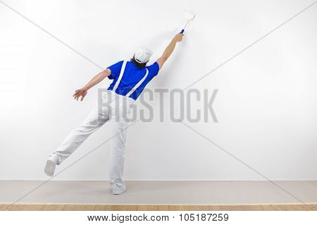 Squatting Painter With Paintroller On White Wall