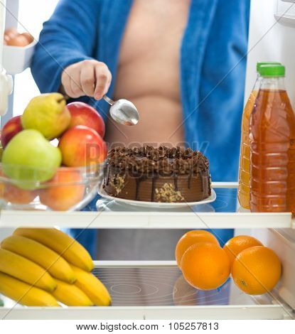 Obese guy prefer to eat big chocolate cake than fresh fruit in fridge