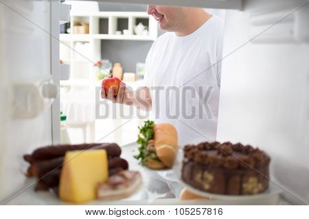 Obese man take apple from fridge instead of high calorie meal from fridge