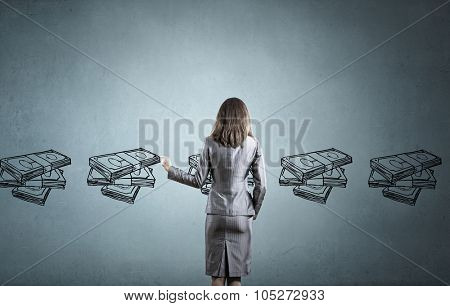Back view of businesswoman drawing money banknotes on wall