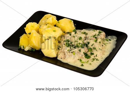 Slices of pork tenderloin with potatoes stewed in cream saucem - served on the black plate. isolated