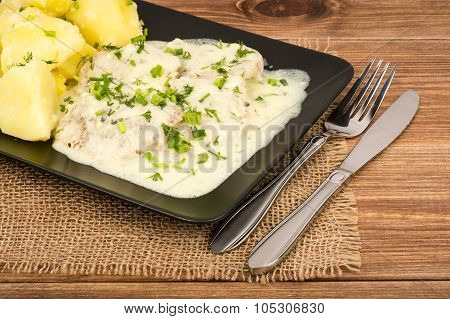 Slices of pork tenderloin with potatoes stewed in cream saucem, served on the black plate.