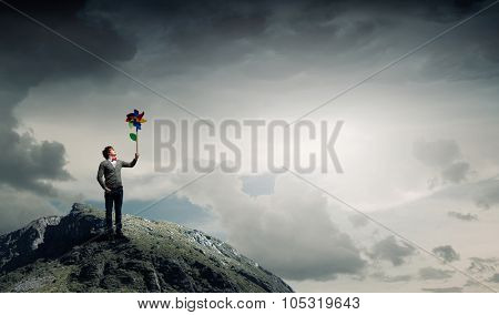 Young happy guy in casual with colorful windmill in hand