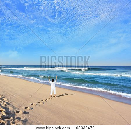  Middle-aged woman dressed in white doing yoga. Huge beautiful beach on the Atlantic coast. The seaside resort of Sintra