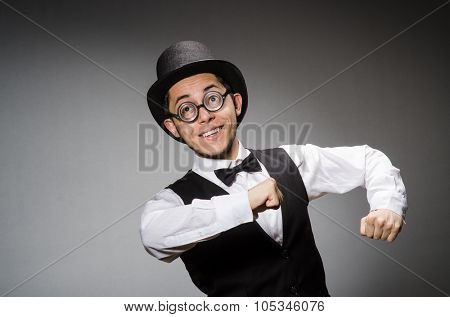 Young man in classical black vest and hat against gray