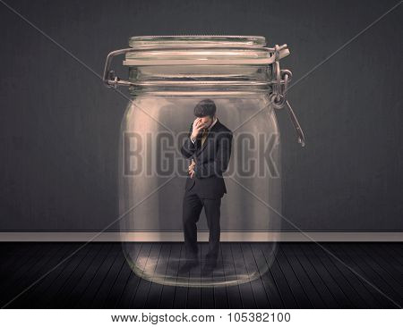Businessman trapped into a glass jar concept on background