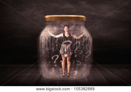 Businesswoman locked into a jar with question marks concept on background