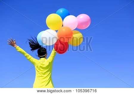 Cheering Young Woman Running On Mountain Peak With Colorful Balloons