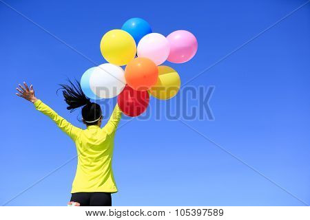 Cheering Young Woman Running On Mountain Peak With Colorful Balloons
