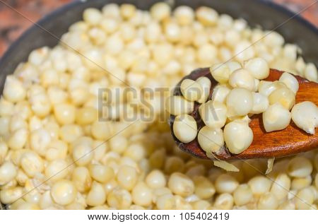 Closeup pot full of cooked corn with wooden spoon scooping up some corns