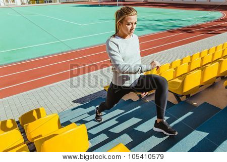 Portrait of a fitness woman doing warm up exercises at stadium