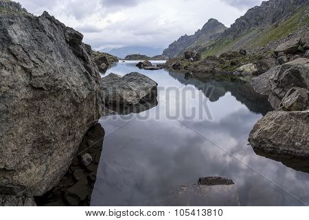 panorama landscape with a lake in the mountains, huge rocks and stones on the coast and reflection o