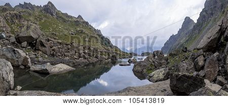 panorama landscape with a lake in the mountains, huge rocks and stones on the coast and reflection o