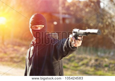 Gunman in black mask holding gun with silencer