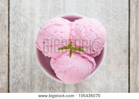 Top view scoops pink ice cream in bowl at rustic wooden vintage table background.