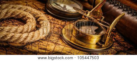 Travel geography navigation concept background - letterbox panorama of old vintage retro compass with sundial, spyglass and rope on ancient world map