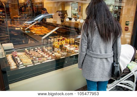 Single Mother Admiring French Sweet Pastry In Bakery Window