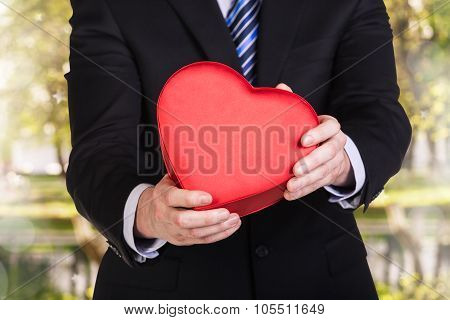 Young man holds red heart box
