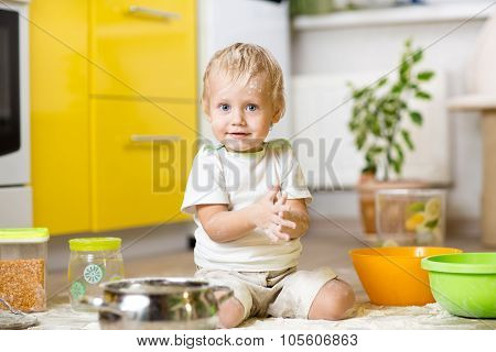 Little boy playing with kitchenware and foodstuffs in kitchen