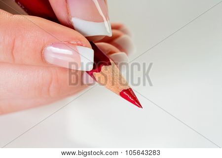 a hand holding a red pen. symbolic photo for savings and budegt cuts.