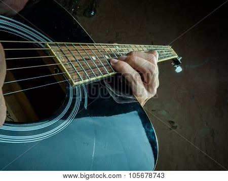 Closeup photo of an acoustic guitar played by a man.