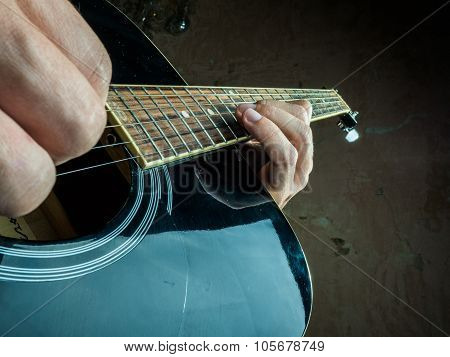 Closeup photo of an acoustic guitar played by a man.