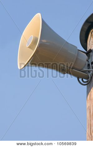 Altoparlante grigio corno sul palo sopra cielo blu