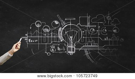 Human hand darwing light bulb as idea concept with chalk