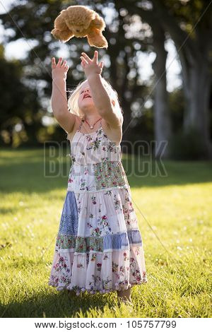 Little Girl Throwing Teddy Bear In The Air