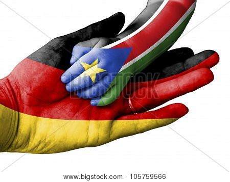 Adult Man Holding A Baby Hand With Germany And South Sudan Flags Overlaid. Isolated On White