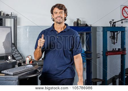 Portrait of happy mechanic gesturing thumbsup at auto repair shop