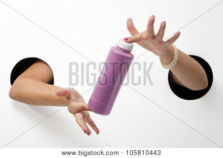 Female  hands through the holes on a white background are holding the disposable packaging with blueberry yogurt