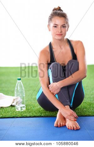 Beautiful young woman relaxing after exerscises on the grass 