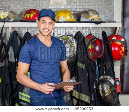 Portrait of confident firefighter holding clipboard at fire station