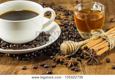 Coffee On The Cup With Coffee Beans, Honey And Cinnamon Sticks On Wood Background, Warm Toning, Sele