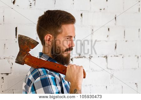 Young bearded lumberjack with red axe