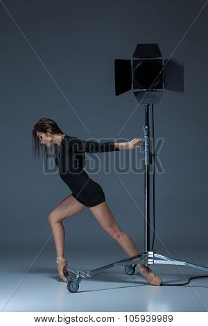 The beautiful ballerina posing on dack blue background