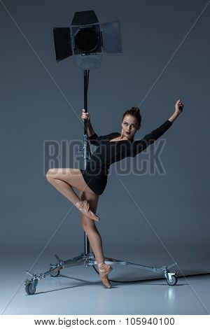 The beautiful ballerina posing on dack blue background