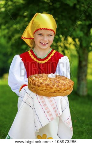 Little girl is dressed in the Russian national dress. She holds in his hands the fresh loaf. It is a custom to meet the guests.