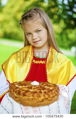 Little girl is dressed in the Russian national dress. She holds in his hands the fresh loaf. It is a custom to meet the guests.