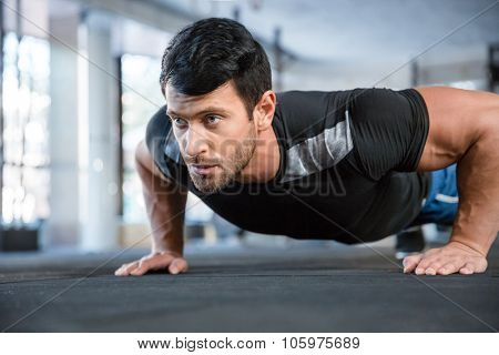 Portrait of a fitness man doing push ups in gym