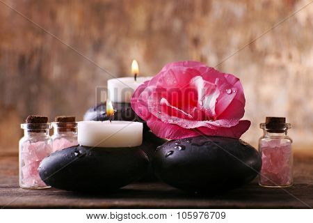 Alight candles, pebbles and fresh aroma flower composition on wooden background