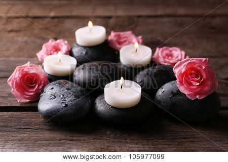 Tenderness relaxing composition with pebbles, roses and candles on wooden background