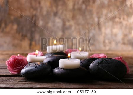 Tenderness relaxing composition with pebbles, roses and candles on wooden background