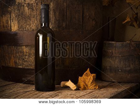 Still life with wine bottles, glasses and oak barrels.