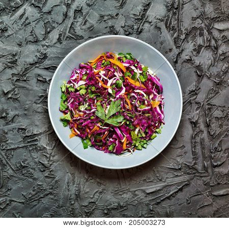Salad healthy food. Red cabbage salad. Fresh vegetable salad with purple cabbage white cabbage salad carrot in a dark clay bowl on a black background. View from above movie effect