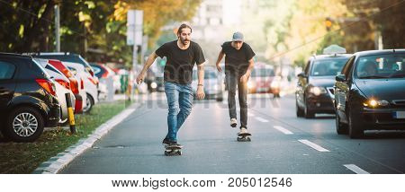 Two Skateboarders Riding Skateboard Slope On The City Streets
